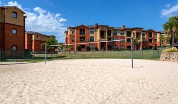 A sandy area in front of a building with a fence.